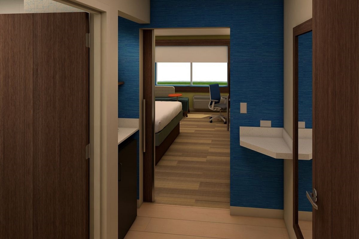 Een hotelkamer met een bed, een bureau, een stoel en een raam met uitzicht.