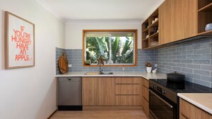 Eine moderne Küche mit Holzausstattung, einem Einbauofen und einem Fenster mit Blick auf Grünflächen.