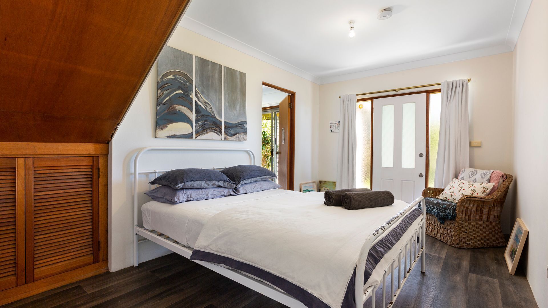A bedroom with a bed, a chair, and a painting on the wall.
