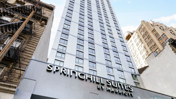 En modern hotellentrén med en skylt som visar texten ”SPRINGHILL SUITES BY MARRIOTT”.