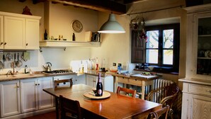 A kitchen with white cabinets, a wooden dining table, and a hanging light fixture.