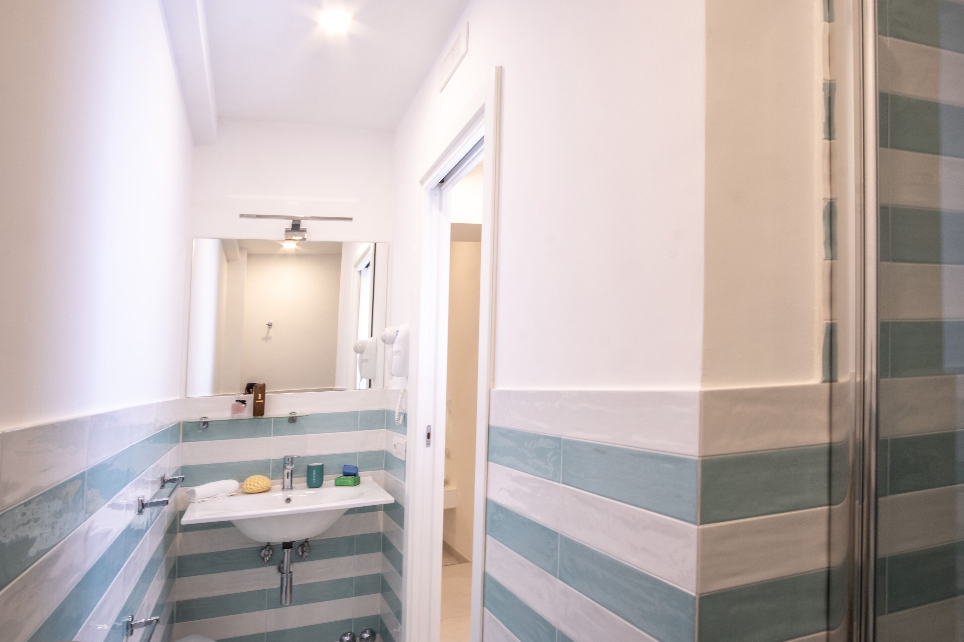 A bathroom with a striped tile design, a sink, and a shower area.