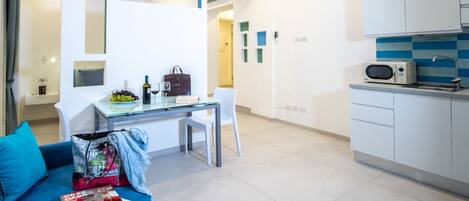Una sala moderna con sofá, una mesa de comedor y una zona de cocina con microondas.