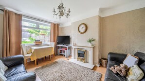 Ein Wohnzimmer mit Kamin, Fernseher, Esstisch und einer Couch.