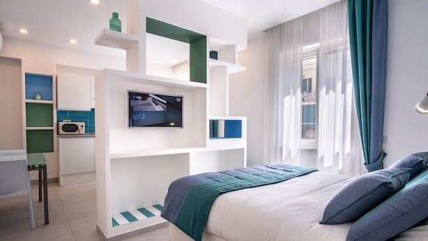 Quarto moderno com cama, televisão e área de trabalho.