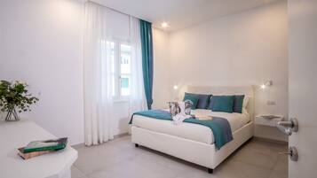 Quarto moderno com cama, mesa de cabeceira e janela com cortinas.