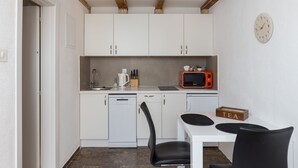 A compact kitchen with white cabinets, a microwave, a coffee maker, and a tea box on the counter. - Apartment Toma (Dubrovnik)