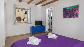 A bedroom with a purple bedspread, a blue dresser, a television, and a painting on the wall. - Apartment Toma (Dubrovnik)