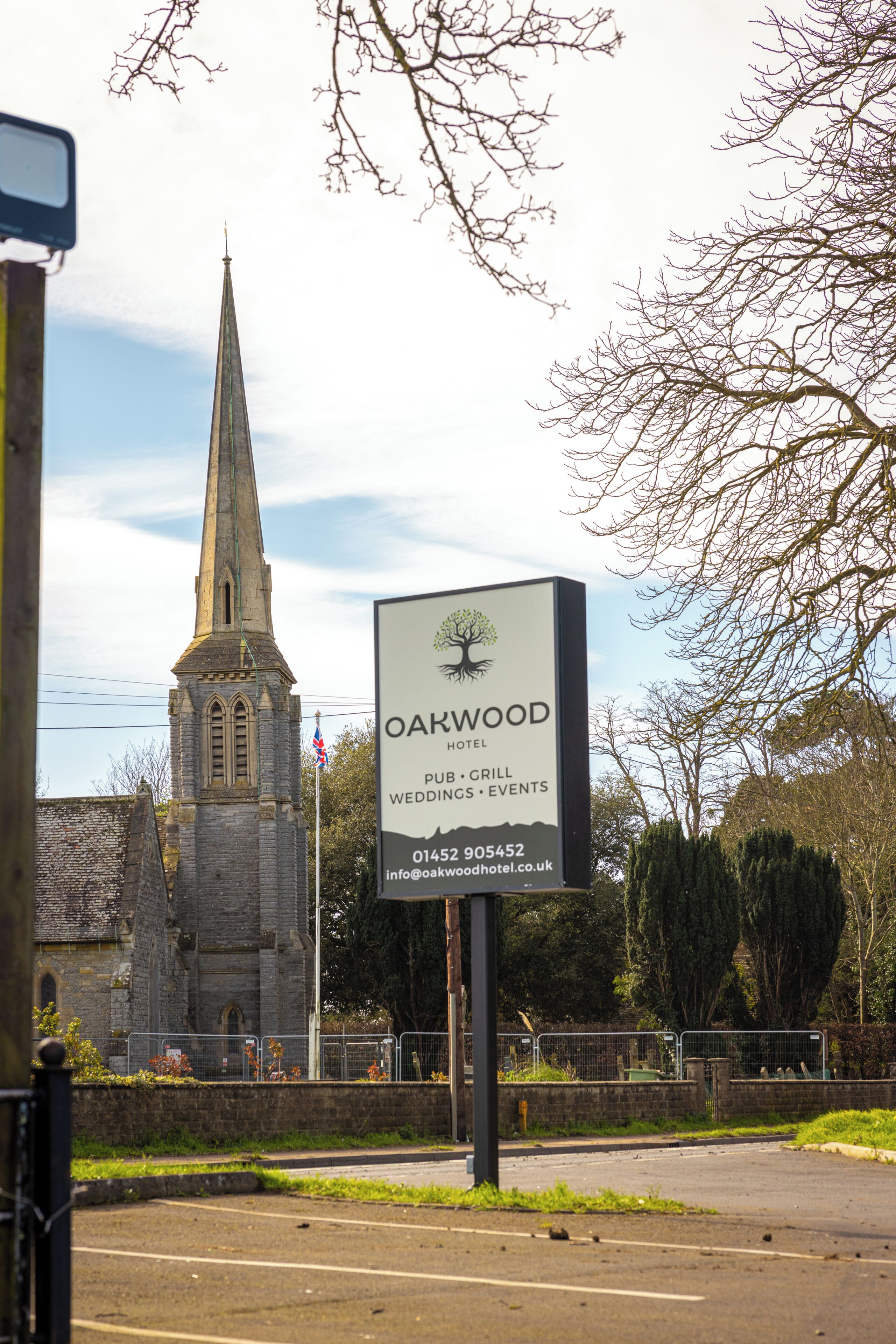 A sign for Oakwood Hotel with a church in the background.
