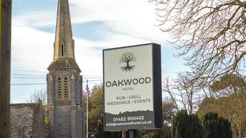 A sign for Oakwood Hotel with a church in the background.