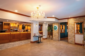 Eine Hotelhalle mit einer Rezeption, einem Kronleuchter, einer Bar und einem Schild mit der Aufschrift 'The Grill'.