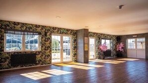 A spacious room with wooden flooring, large windows, and a decorative wall.