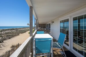 Ein Balkon mit Blick auf den Strand, einem Tisch und zwei Stühlen.