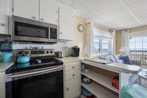 A compact kitchen with a microwave, stove, and coffee maker.