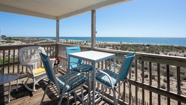 A covered outdoor area with a table and chairs, overlooking a beach. - North OC, charming 2 bedroom oceanfront with Friday to Friday stay (Ocean City)