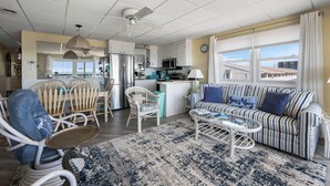 A spacious living area with a sofa, chairs, a coffee table, and a kitchen in the background. - North OC, charming 2 bedroom oceanfront with Friday to Friday stay (Ocean City)