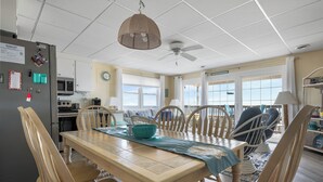 A dining area with a wooden table, chairs, a ceiling fan, and a view of the ocean. - North OC, charming 2 bedroom oceanfront with Friday to Friday stay (Ocean City)