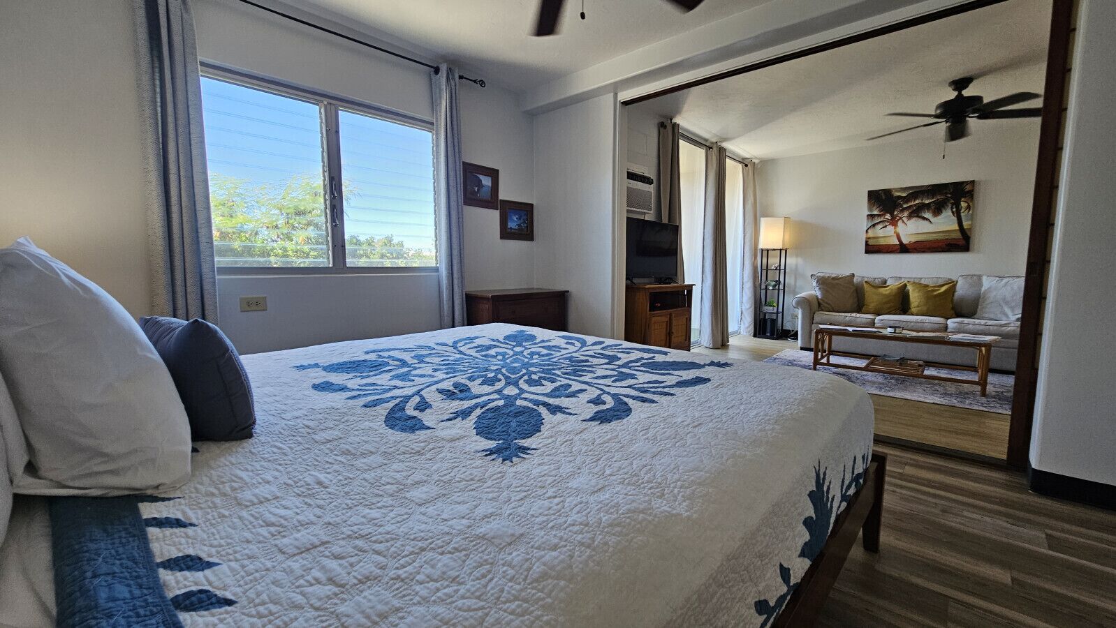 A hotel room with a large bed, a sofa, a TV, and a ceiling fan.