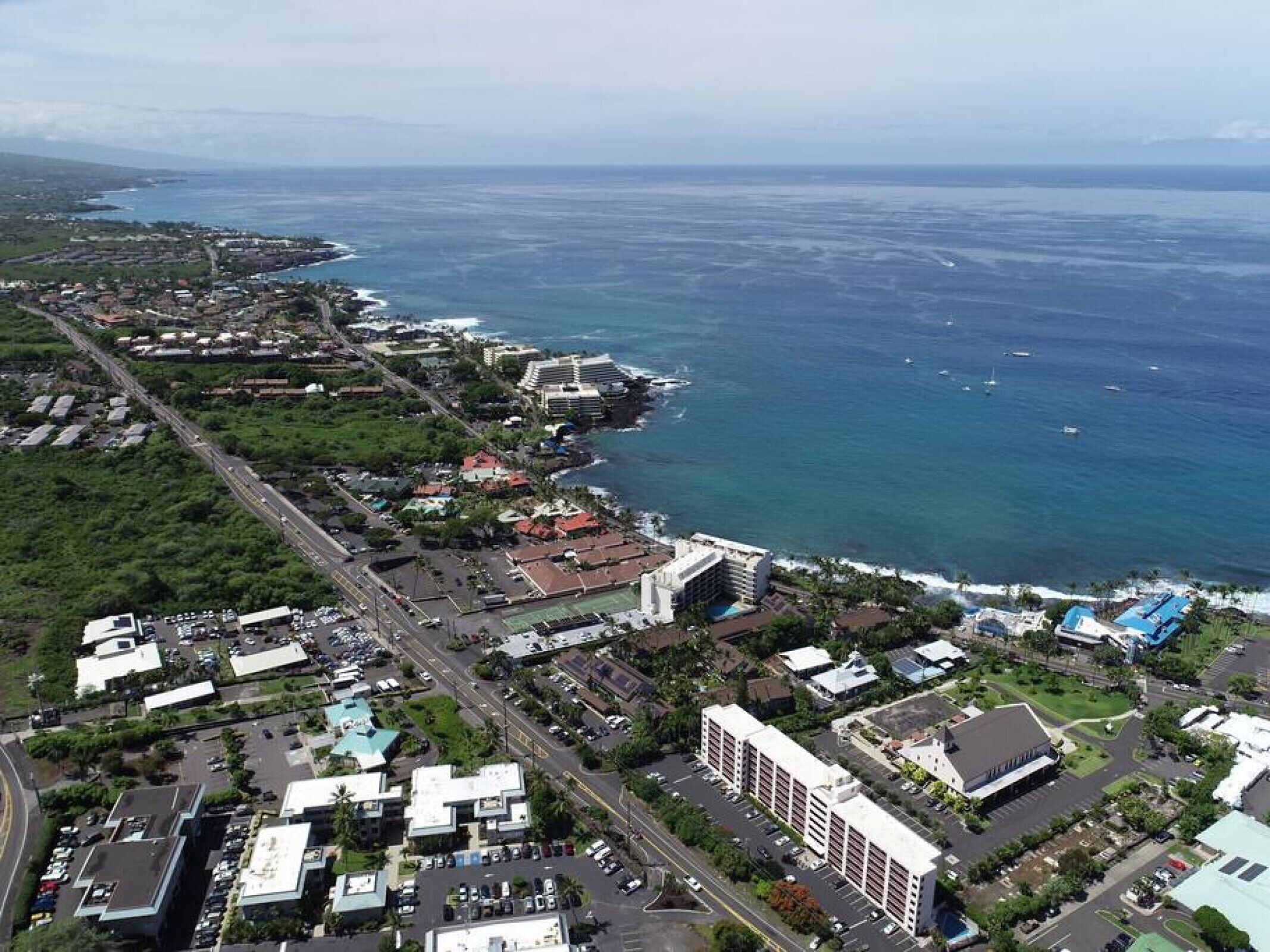 Vista aérea de una zona costera con edificios, carreteras y un puerto deportivo.