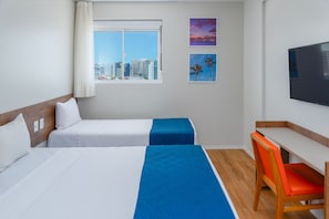 A hotel room with two beds, a desk, a chair, a television, and a window with a city view. - Verano Pajucara By Tropicalis (Maceió)