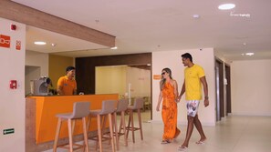 A hotel reception area with a counter, bar stools, and a sign indicating a 'Foyer'. - Verano Pajucara By Tropicalis (Maceió)