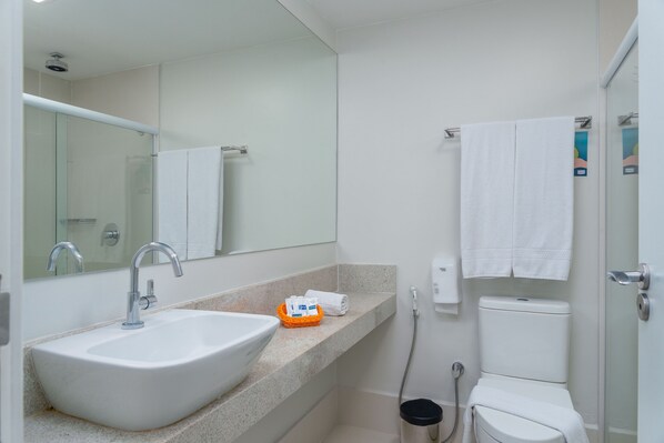 Un baño con lavamanos blanco, un espejo, toallero y un inodoro.