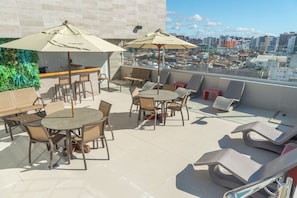 A rooftop terrace with outdoor seating, including tables and chairs, and umbrellas. - Verano Pajucara By Tropicalis (Maceió)