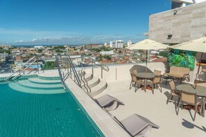 A rooftop pool with a view of the city, outdoor seating, and a staircase leading down to the pool. - Verano Pajucara By Tropicalis (Maceió)