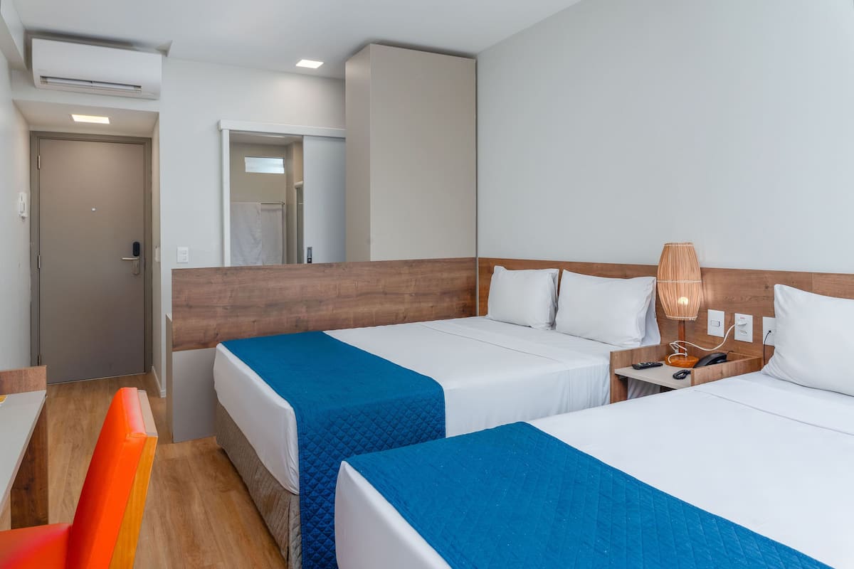 Ein Hotelzimmer mit zwei Betten, einem Holzkopfteil, einem Schreibtisch und einem Stuhl.