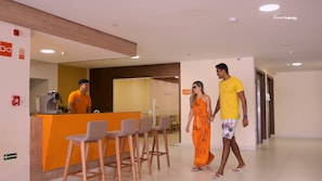 A hotel reception area with a counter, bar stools, and a sign indicating a 'Foyer'. - Verano Pajucara By Tropicalis (Maceió)