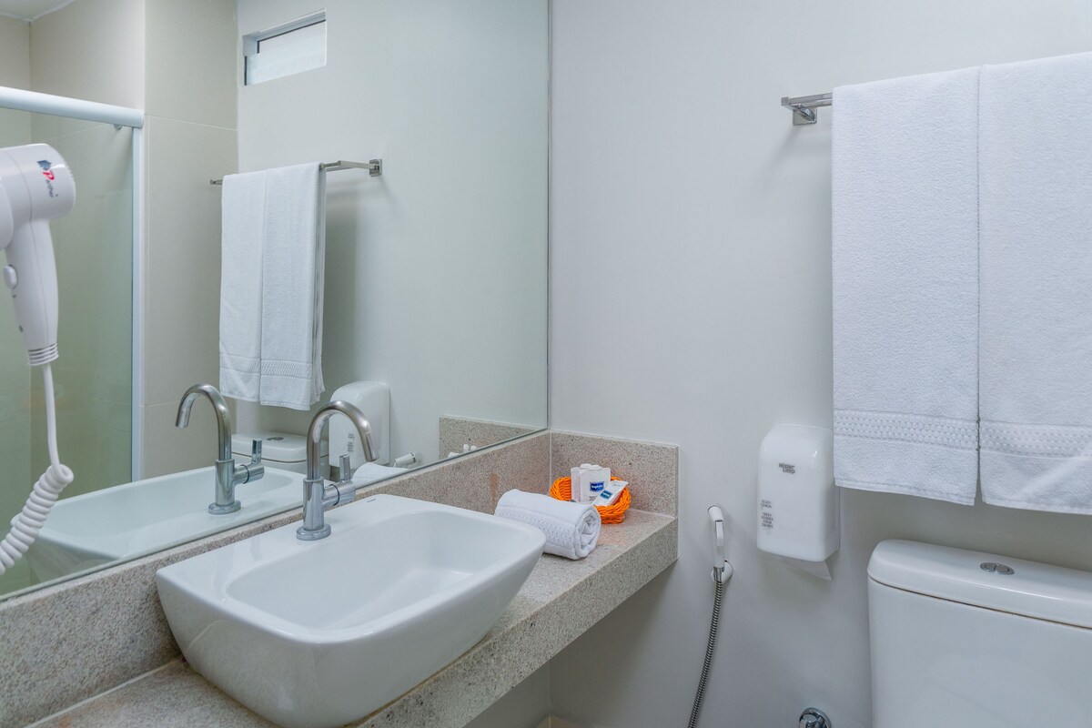 A bathroom with a sink, mirror, towel rack, and a hand dryer.