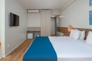 A hotel room with a bed, a TV, a desk, and a small kitchenette. - Verano Pajucara By Tropicalis (Maceió)