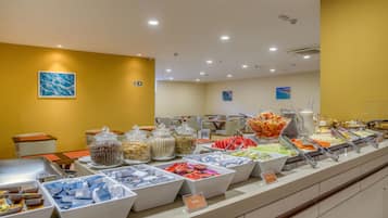 Un área de bufé con diversas opciones de comida y diferentes disposiciones de mesas.