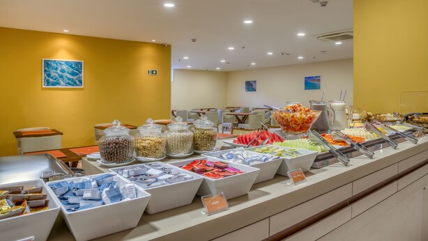 A buffet area with various food options and seating arrangements. - Verano Pajucara By Tropicalis (Maceió)