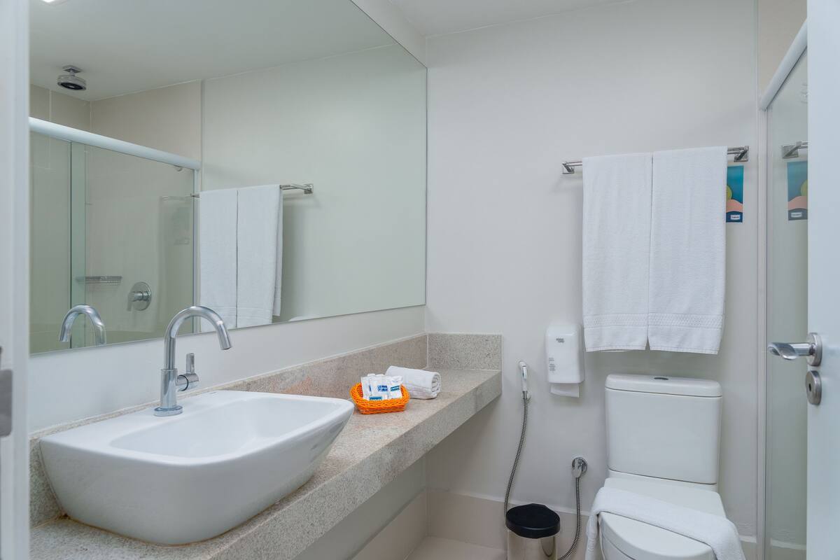 Ein modernes Badezimmer mit einem weißen Waschbecken, einer Duschkabine aus Glas und einer Toilette.