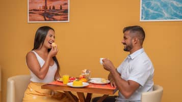 Una mesa de comedor con platos de comida, un vaso de jugo de naranja y una taza.