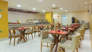 A cafeteria with multiple tables and chairs, equipped with a buffet area in the background. - Verano Pajucara By Tropicalis (Maceió)