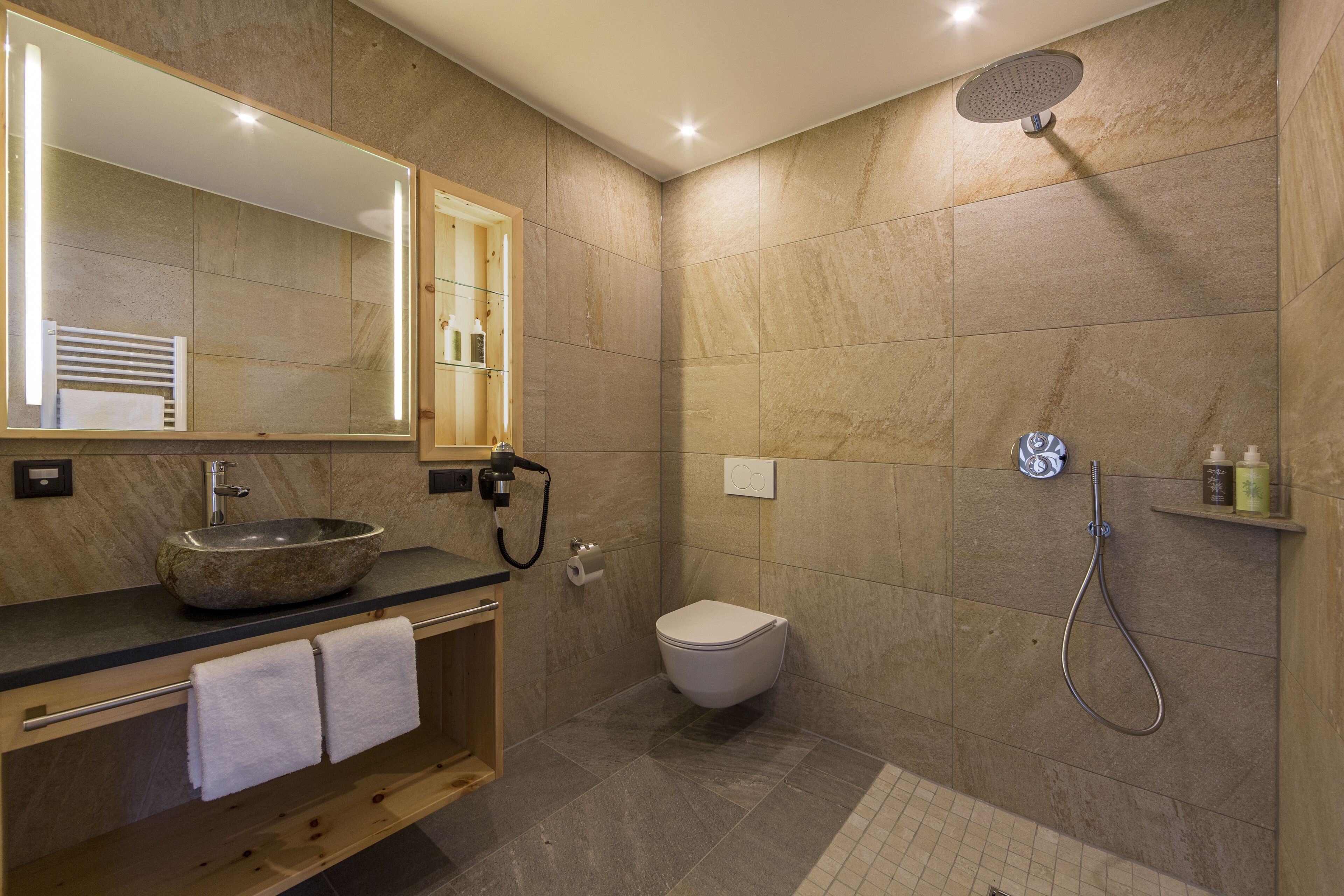 A modern bathroom with a stone sink, a toilet, and a shower.