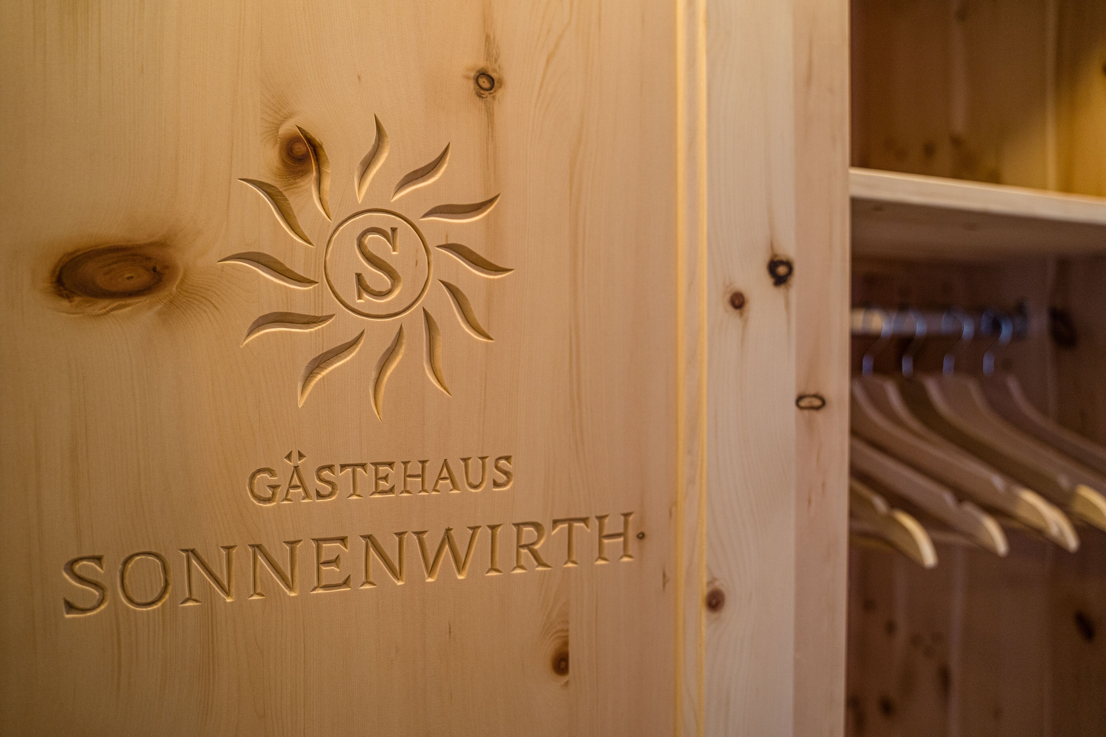 A wooden door with a sun emblem and the text "GÄSTEHAUS SONNENWIRTH".