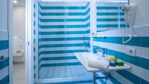 A bathroom with a glass shower enclosure, a sink with a mirror, and a hairdryer mounted on the wall. - Family Apartment in Sorrento Centre (Sorrento)