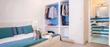 A bedroom with a bed, a wardrobe, and a bathroom with a sink and mirror.