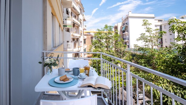 A balcony with a table set for breakfast, overlooking a residential area with buildings and trees. - Family Apartment in Sorrento Centre (Sorrento)