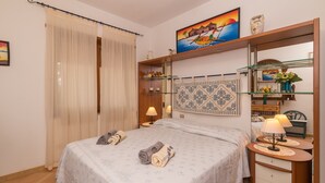Ein Schlafzimmer mit Bett, Nachttisch, Spiegel, einer Ablage mit Dekoration und einem Bild an der Wand.