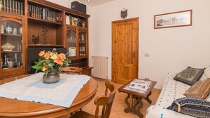 Ein Essbereich mit Holztisch, Stühlen, einer Blumenvase, einem Bücherregal und einer Holztür.