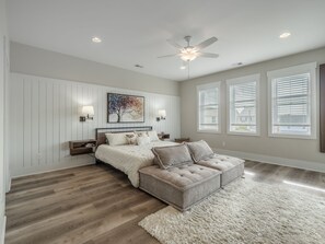 Relax in this stylish bedroom with a large bed, nightstands, and a unique tree artwork above.