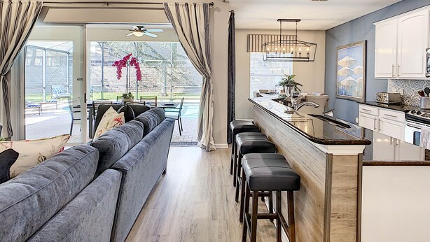 Eine moderne Küche mit Barbereich, einem großen Fenster und einer Sitzecke mit einer Couch und Barhocker.