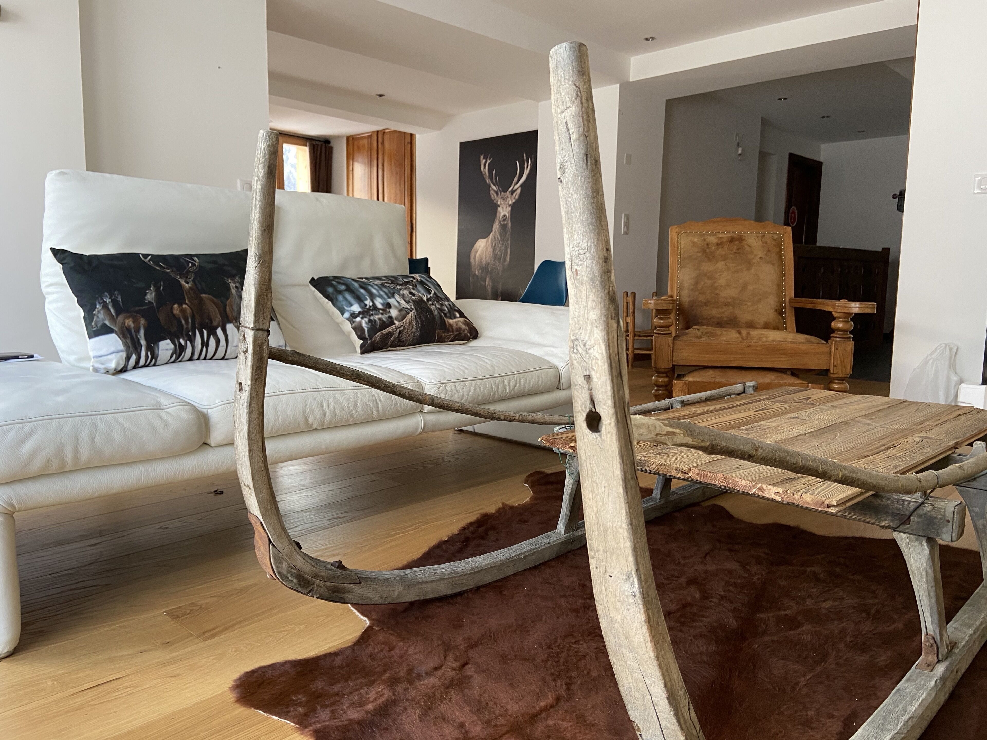 Un salon avec un canapé blanc, une table basse en bois et un tapis marron à poils longs.