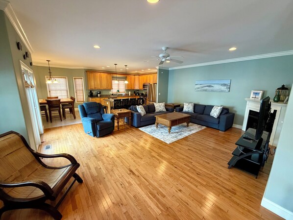 A spacious living area with a dining table, sofas, a coffee table, and a fireplace.