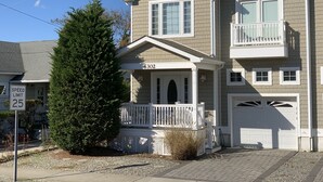 Une maison à deux étages avec un porche à l’avant, un garage et un balcon.