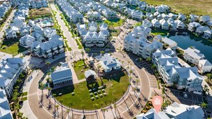Una zona residencial costera con casas modernas, una rotonda central y vista al océano.